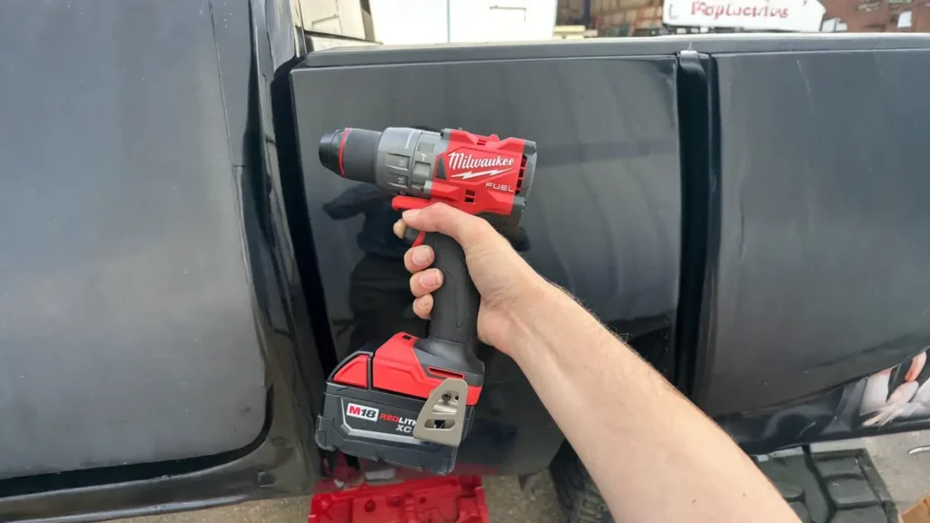 A close-up shot of a person holding the Milwaukee 2904-20 M18 Fuel Hammer Drill, highlighting its compact body and large battery pack.