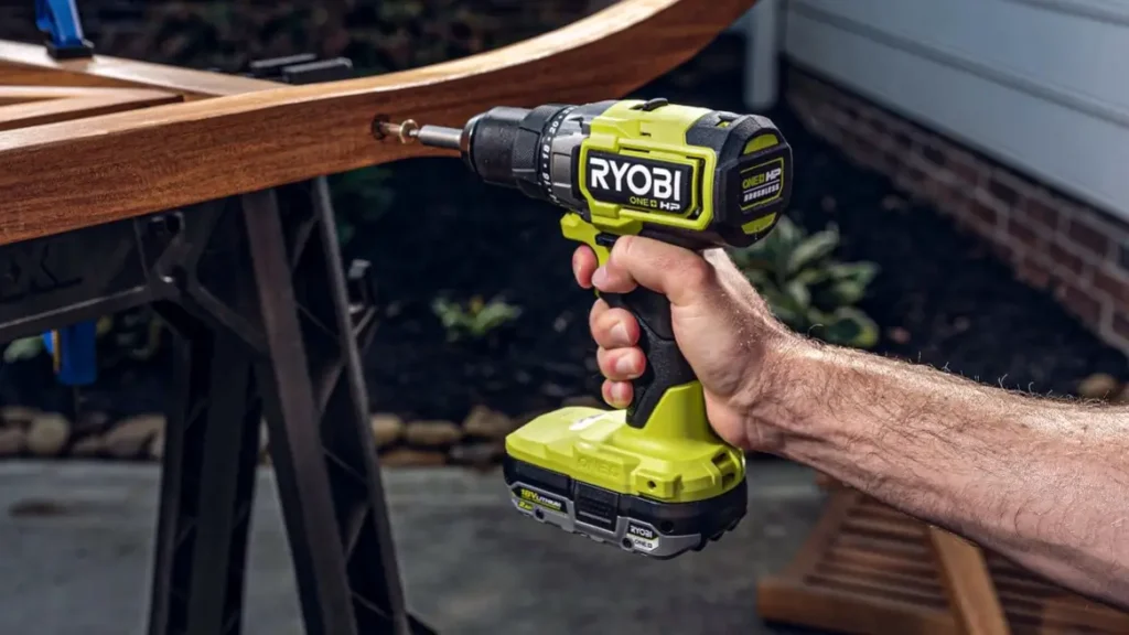 A person using the green and black Ryobi PBLHM102 18V drill to work on a curved piece of wooden furniture, demonstrating its use for home projects.