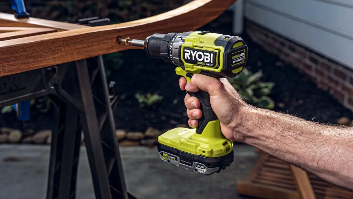 A person using the green and black Ryobi PBLHM102 18V drill to work on a curved piece of wooden furniture, demonstrating its use for home projects.