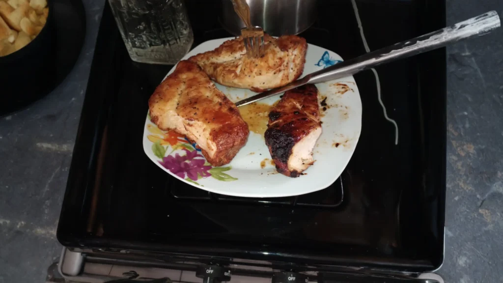 Three pieces of perfectly seared and charred chicken breast served on a floral plate.