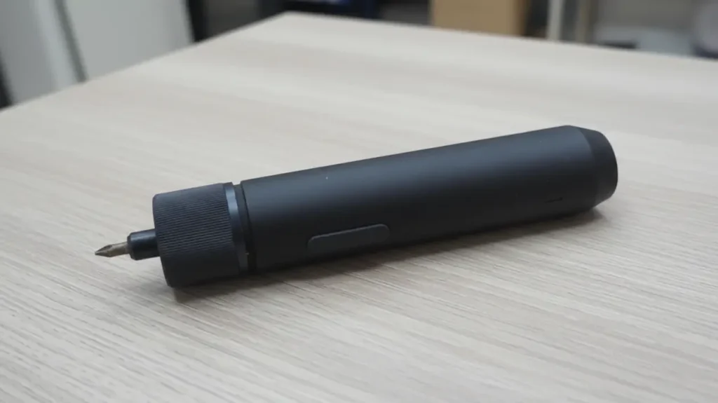 Close-up of the USB-C charging port at the base of the HOTO electric screwdriver on a workshop table.