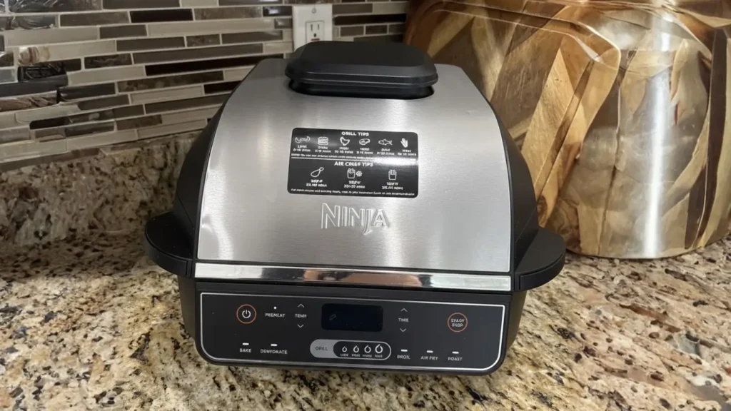 A sleek silver and black Ninja Foodi Smart XL 6-in-1 Indoor Grill sitting on a granite countertop, reviewed by Tool Tested.