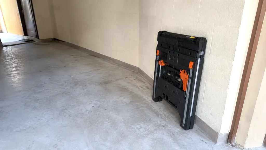 Collapsed portable workbench leaning against a garage wall