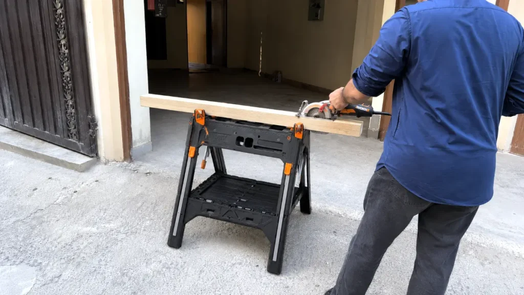 Portable work table folded down into sawhorse mode holding lumber