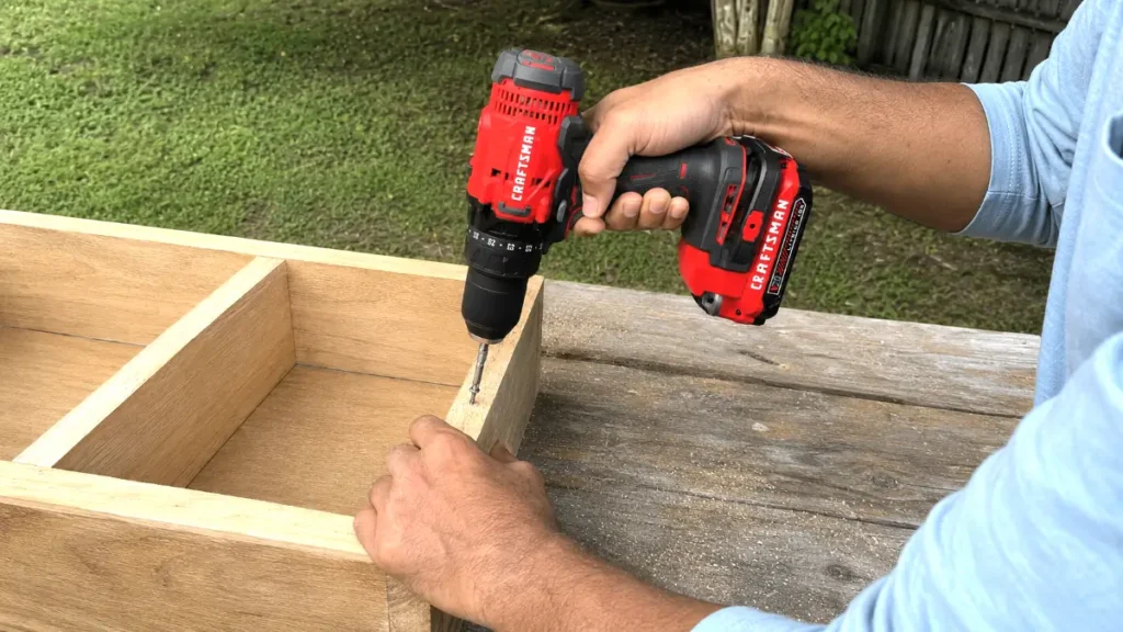 Driving a screw flush into a wooden furniture joint using a cordless power tool.
